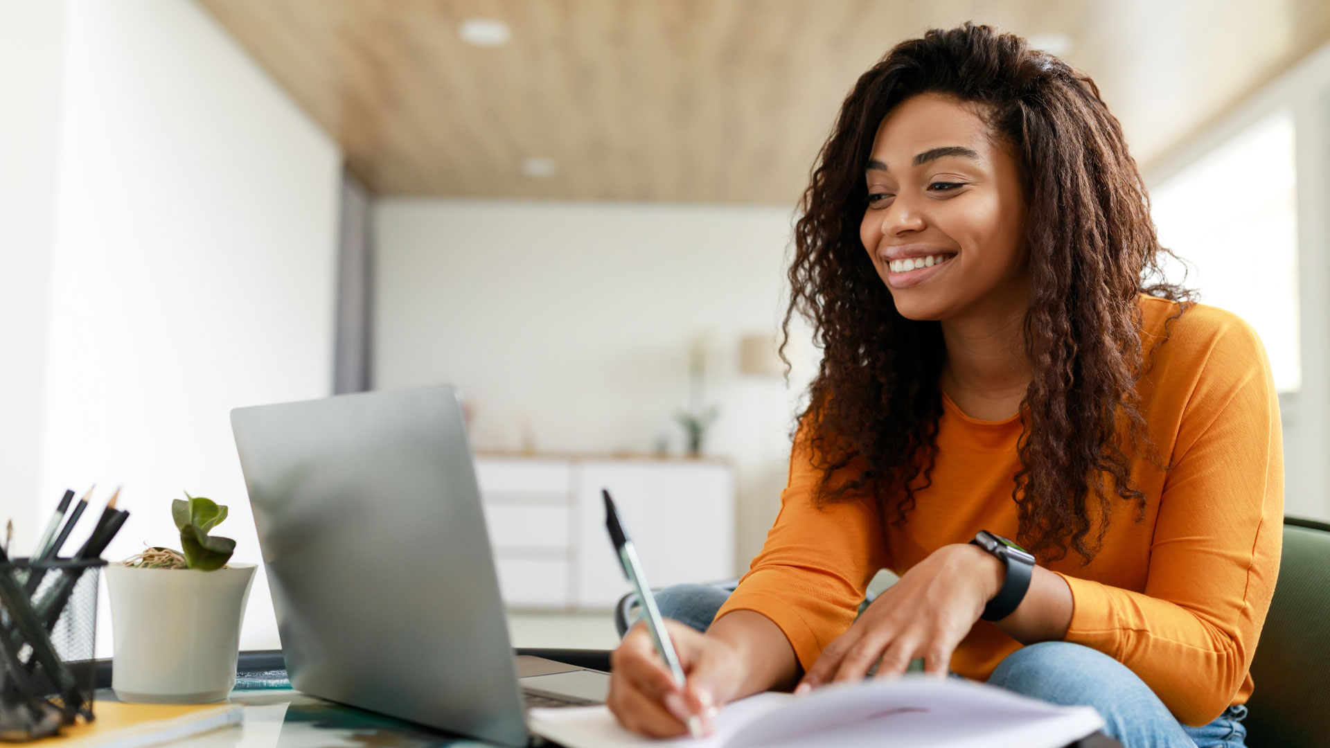 School student connecting to an online class on a laptop, smiling.