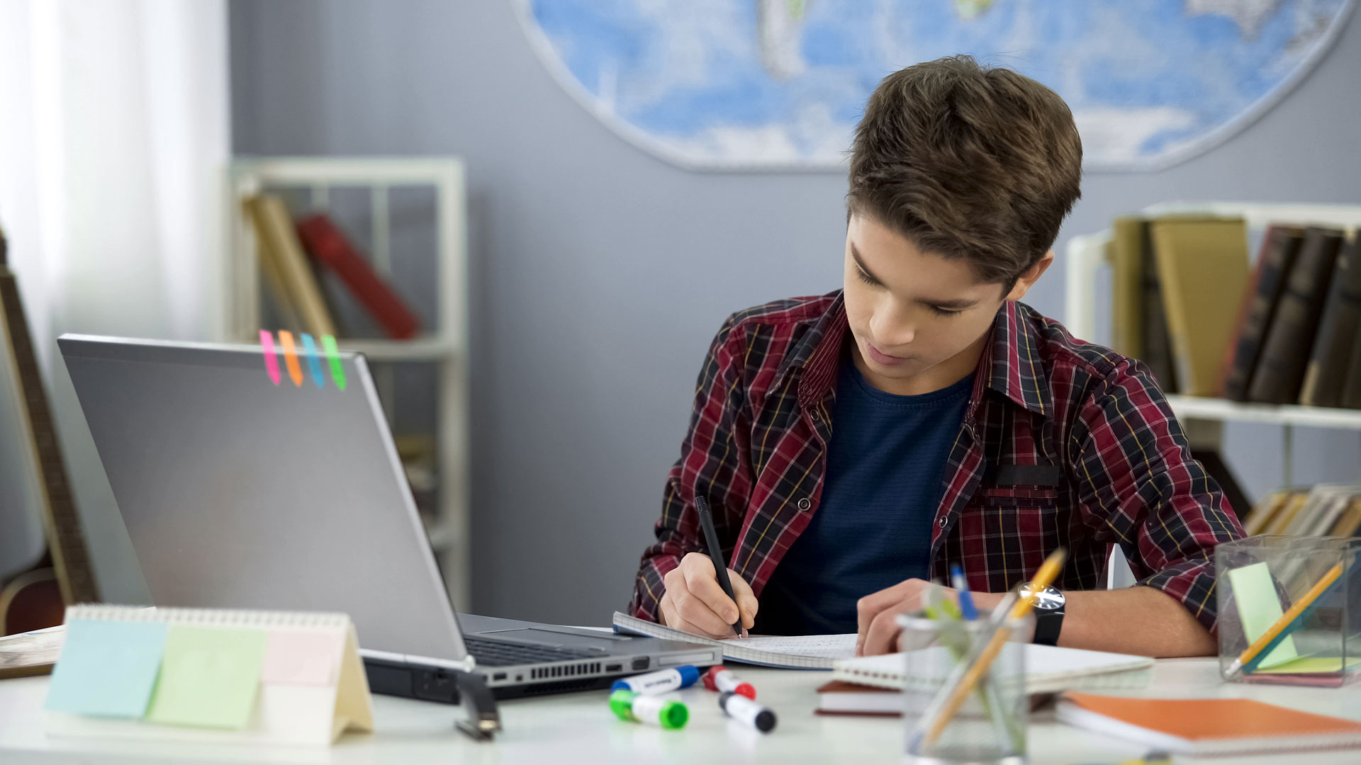 School student connecting to an online class, making notes for revision.